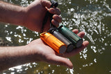 Three Storm-Strike EDC Canisters held in hand by the water