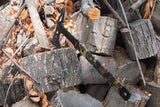 Hatchet with a camo TITAN Battle Tape wrapped handle resting on split firewood
